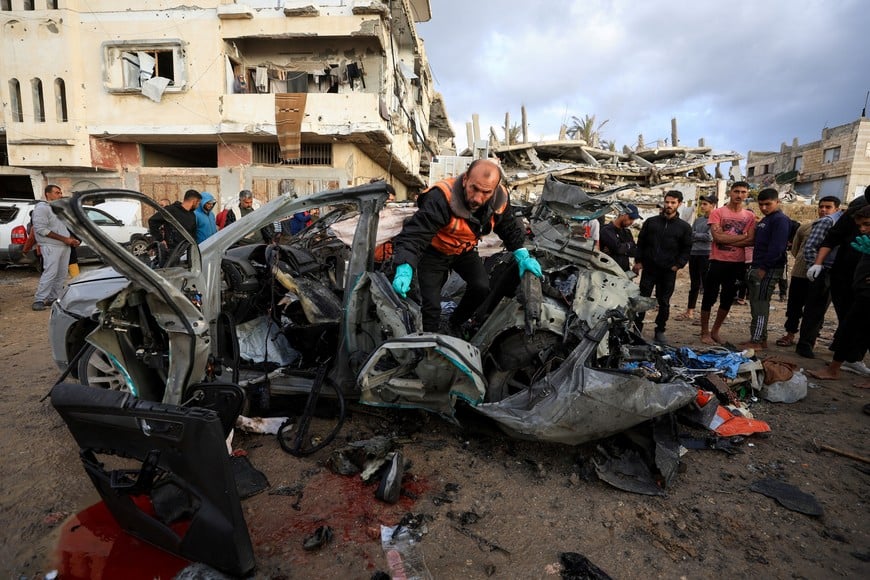 Palestinians inspect the site of an Israeli strike on a car in Gaza City, December 13, 2025.REUTERS/Dawoud Abu Alkas