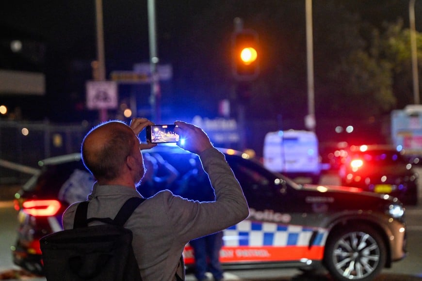 A man records a video at the scene of a shooting incident at Bondi Beach, Sydney, Australia, December 14, 2025. REUTERS/Izhar Khan
