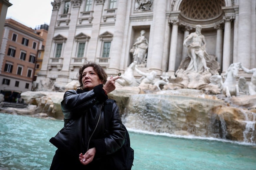 Carola, from Chile, throws a coin into the Trevi Fountain in Rome, Italy, February 19, 2024. As visitors' coins splash into Rome's majestic Trevi Fountain carrying wishes for love, good health or a return to the Eternal City, they provide practical help to people the tourists will never meet. For hundreds of years, when in Rome, visitors have flocked to the fountain to make a wish, following a storied ritual. Few gave their coins a second thought. Today, coins pile up for several days before they are fished out and taken to the Rome division of the worldwide Catholic charity Caritas, which counts the bucketfuls of change and uses them to fund a food bank, soup kitchen and welfare projects. "I am tossing a coin as they say if you toss a coin you come back to Rome, and also because I want to make the wish to find love," Carola said. REUTERS/Guglielmo Mangiapane SEARCH "MANGIAPANE FOUNTAIN COINS" FOR THIS STORY. SEARCH "WIDER IMAGE" FOR ALL STORIES.