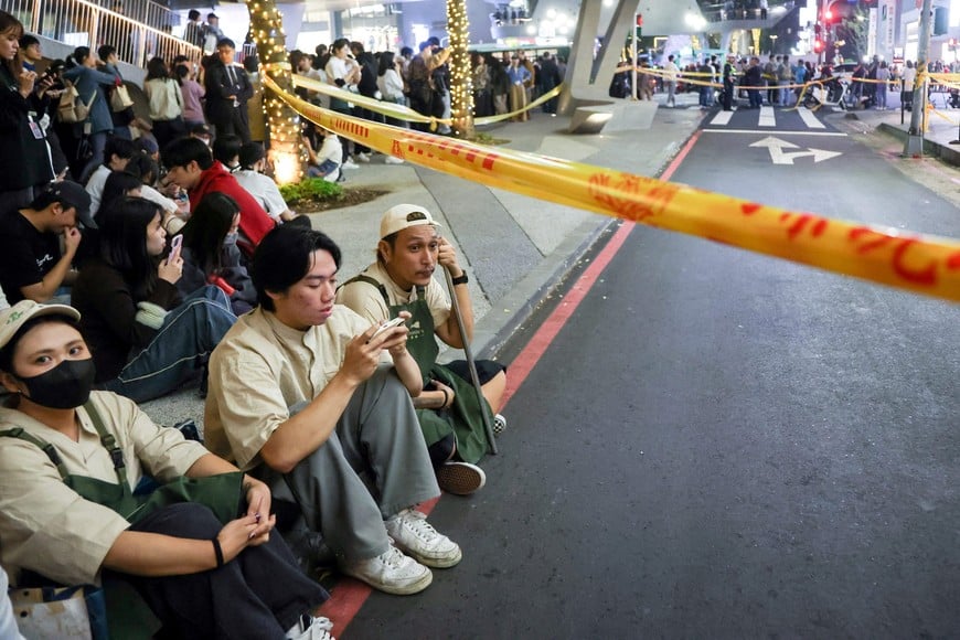 Staff from Eslite Spectrum Nanxi store near Zhongshan station wait to return to the building to collect their personal belongings while the building is cordoned off with yellow crime scene tape, following an incident in which several were injured after a person released smoke bombs and attacked bystanders, according to the government and local media, in Taipei, Taiwan, December 19, 2025. REUTERS/Ann Wang