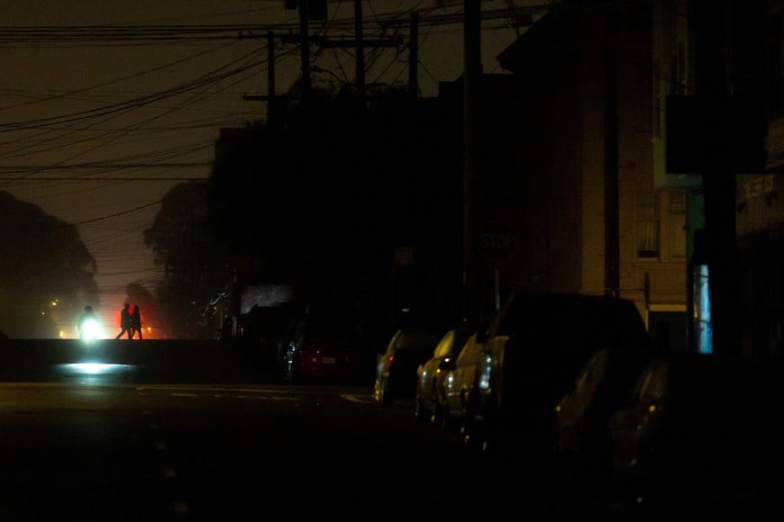People cross an intersection in the dark during a blackout that affected about 130,000 residents, according to Pacific Gas and Electric Company in San Francisco, California, U.S., December 21, 2025. REUTERS/Carlos Barria