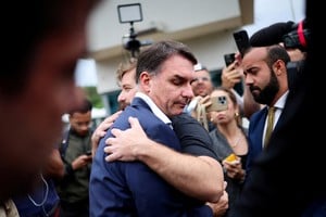 Senator Flavio Bolsonaro, Brazil's former President Jair Bolsonaro's son, is being hugged by a supporter, after visiting his father at the Federal Police building, where the former president is kept in custody after an ankle monitor breach while on house arrest, in Brasilia, Brazil, November 25, 2025. REUTERS/Mateus Bonomi     TPX IMAGES OF THE DAY
