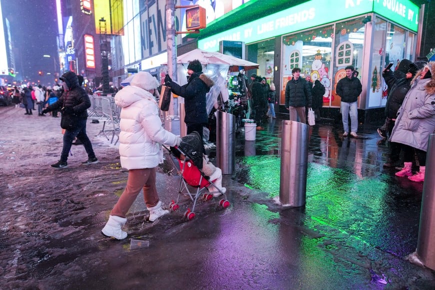 A person pushes a stroller through a puddle in Times Square during a winter storm in New York City, U.S., December 26, 2025. REUTERS/Adam Gray