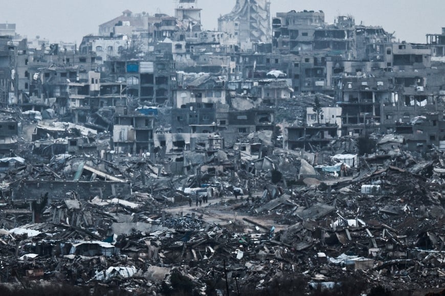 Palestinians walk near damaged buildings in the Gaza Strip , as seen from Israel's border with Gaza, Israel, December 29, 2025. REUTERS/Amir Cohen     TPX IMAGES OF THE DAY
