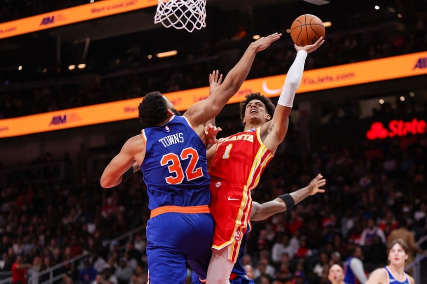 Dec 27, 2025; Atlanta, Georgia, USA; Atlanta Hawks forward Jalen Johnson (1) shoots around New York Knicks center Karl-Anthony Towns (32) in the fourth quarter at State Farm Arena. Mandatory Credit: Brett Davis-Imagn Images