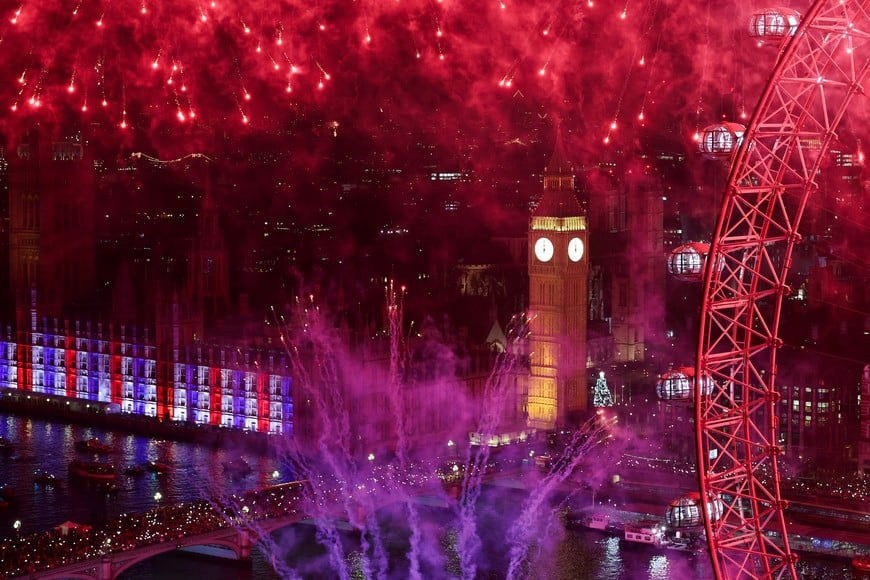 Crowds gather on the Westminster Bridge with the illuminated Houses of Parliament in the background as fireworks explode over the Elizabeth Tower, commonly referred to as Big Ben, and the London Eye Ferris wheel, to mark the New Year's celebrations, in London, Britain, January 1, 2026. REUTERS/Toby Melville      TPX IMAGES OF THE DAY