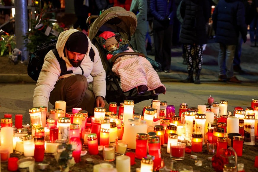 A man places a candle at a makeshift memorial near the "Le Constellation" bar, after a fire and explosion during a New Year's Eve party in which people died and others were injured, in the upscale ski resort of Crans-Montana in southwestern Switzerland, January 2, 2026. REUTERS/Denis Balibouse
