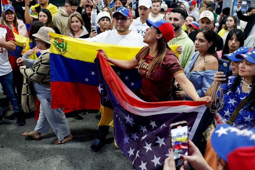 People hold a Venezuelan and U.S. flag, as they react to the news after U.S. President Donald Trump said the U.S. has struck Venezuela and captured its President Nicolas Maduro, on the streets of Miami, Florida, U.S., January 3, 2026. REUTERS/Marco Bello     TPX IMAGES OF THE DAY