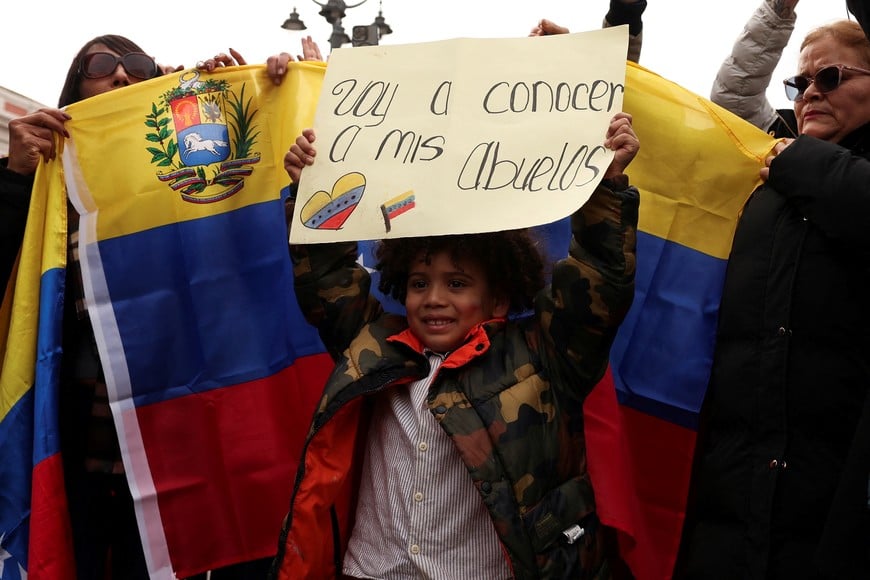 A child holds a placard saying "I will meet my grandparents" as people react to the news after U.S. President Donald Trump said the U.S. has struck Venezuela and captured its President Nicolas Maduro, in Madrid, Spain, January 3, 2026. REUTERS/Violeta Santos Moura