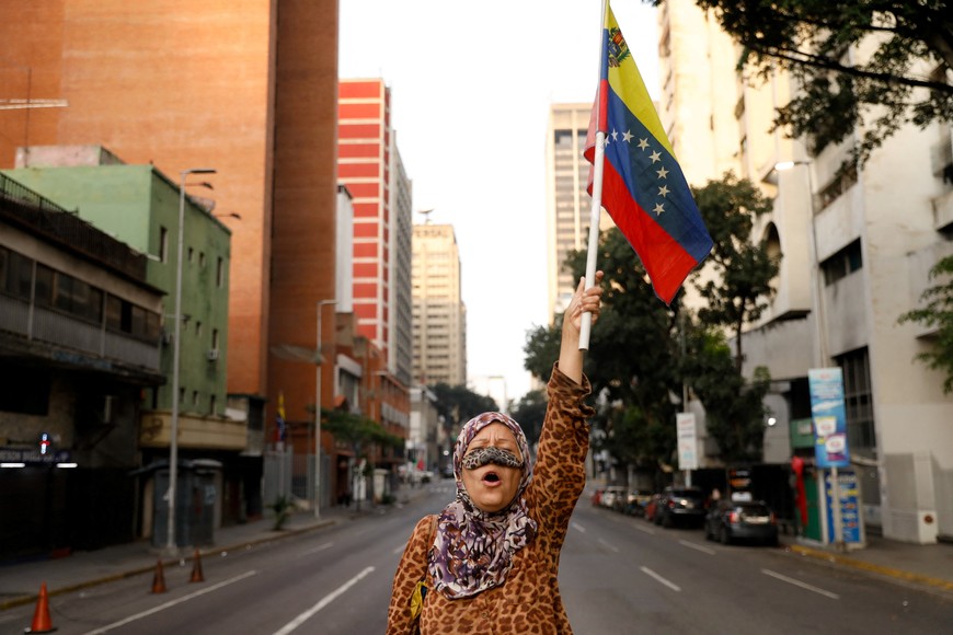 A supporter of Venezuelan President Nicolas Maduro holds a flag of Venezuela on a street near Miraflores Palace, after U.S. President Donald Trump said the U.S. has struck Venezuela and captured Maduro, in Caracas, Venezuela, January 3, 2026.  REUTERS/Leonardo Fernandez Viloria