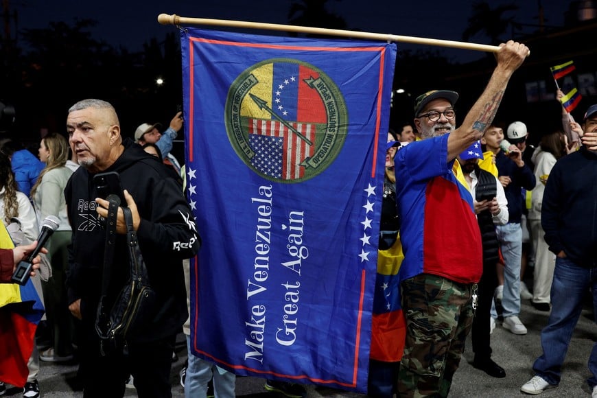 A man holds a flag reading "Make Venezuela Great Again", as people react to the news after U.S. President Donald Trump said the U.S. has struck Venezuela and captured its President Nicolas Maduro, in Doral, Miami, Florida, U.S., January 3, 2026. REUTERS/Marco Bello