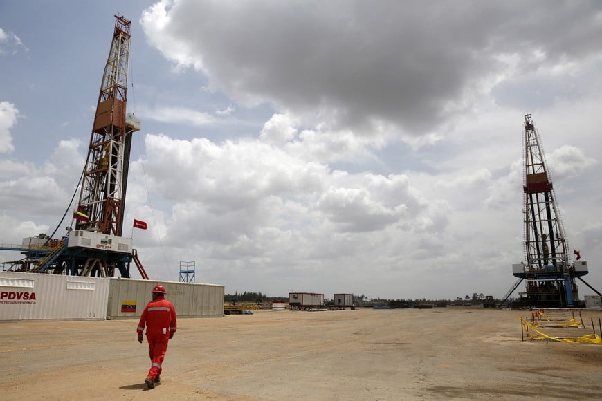 FILE PHOTO: An oilfield worker walks next to drilling rigs at an oil well operated by Venezuela's state oil company PDVSA, in the oil rich Orinoco belt, near Morichal at the state of Monagas April 16, 2015. Picture taken on April 16, 2015. REUTERS/Carlos Garcia Rawlins/File Photo