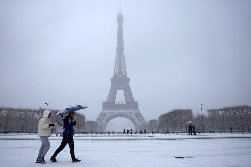 People walk on the snow-covered Champs de Mars near the Eiffel Tower in Paris, as winter weather with snow and cold temperatures hits a large part of the country, France, January 5, 2026. REUTERS/Abdul Saboor