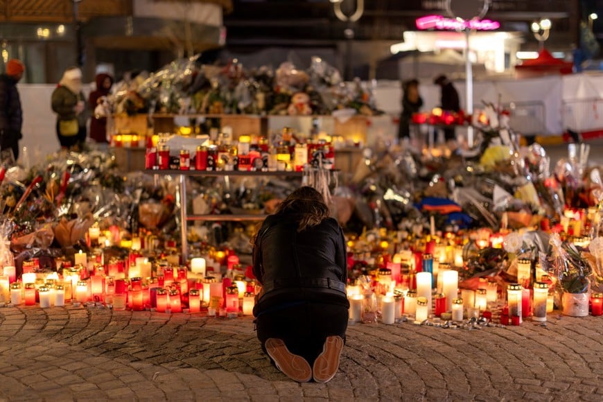 A woman lights a candle at a makeshift memorial outside the "Le Constellation" bar, after a deadly fire and explosion during a New Year's Eve party, in the upscale ski resort of Crans-Montana in southwestern Switzerland, January 5, 2026. REUTERS/Umit Bektas