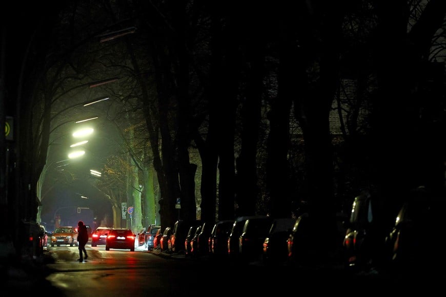 A person crosses the street as cars drive during a blackout, which left thousands of homes without power after a suspected arson attack at the Lichterfelde power plant in the Steglitz-Zehlendorf district in southern Berlin, Germany, January 6, 2026. REUTERS/Lisi Niesner