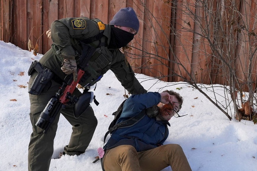 A member of U.S. Immigration and Customs Enforcement (ICE) restrains a protester trying to block vehicles from leaving the scene after a driver of a vehicle was shot in Minneapolis, Minnesota, U.S., January 7, 2026.  REUTERS/Tim Evans     TPX IMAGES OF THE DAY