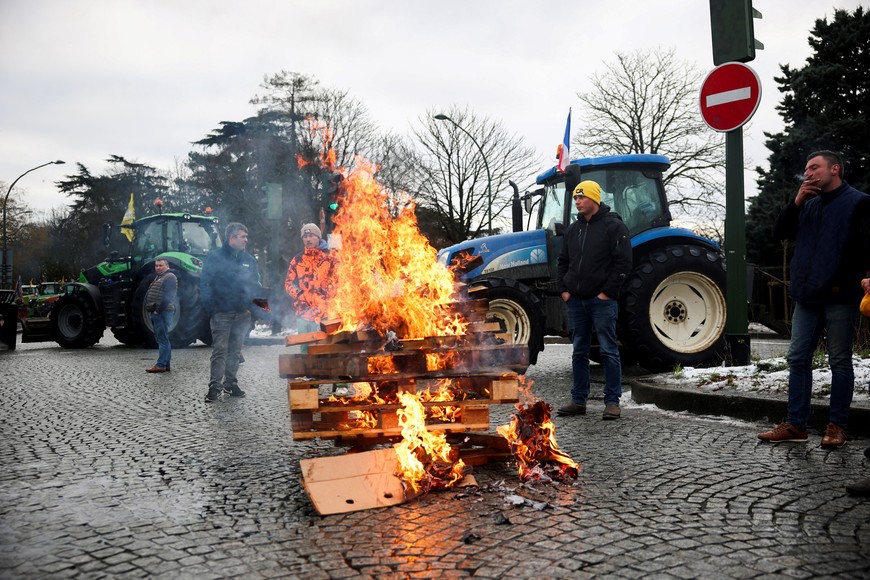 Farmers stand next to burning pallets as tractors are parked at Porte d'Auteuil, during French farmers' protest against the government's handling of the EU-Mercosur free trade agreement and the handling of the lumpy skin disease outbreak, in Paris, France January 8, 2026. REUTERS/Gonzalo Fuentes