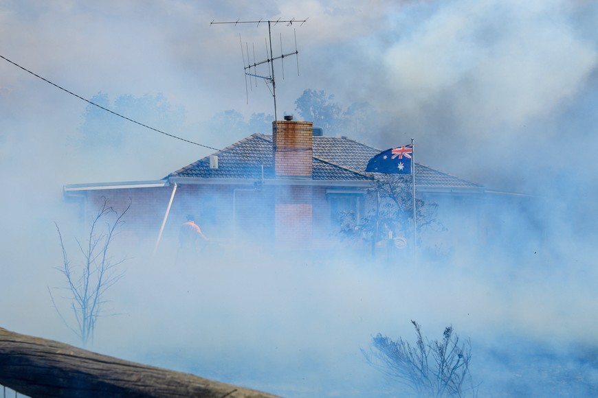 An Australian flag waves as Country Fire Authority (CFA) members douse a home in Longwood in Victoria, Australia January 9, 2026. AAP/Michael Currie/via REUTERS ATTENTION EDITORS - THIS IMAGE WAS PROVIDED BY A THIRD PARTY. NO RESALES. NO ARCHIVES. AUSTRALIA OUT. NEW ZEALAND OUT. NO COMMERCIAL OR EDITORIAL SALES IN NEW ZEALAND. NO COMMERCIAL OR EDITORIAL SALES IN AUSTRALIA.