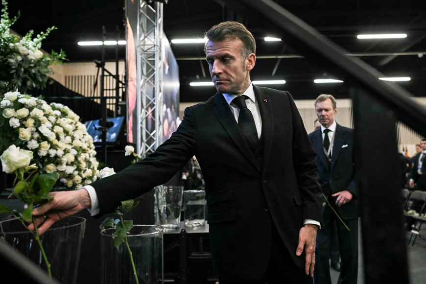 France's President Emmanuel Macron places a white rose at a makeshift floral memorial after the tribute ceremony for the victims of the deadly fire that ripped through the bar Le Constellation in Crans-Montana on New Year's Eve, in Martigny, Switzerland on January 9, 2026. FABRICE COFFRINI/Pool via REUTERS