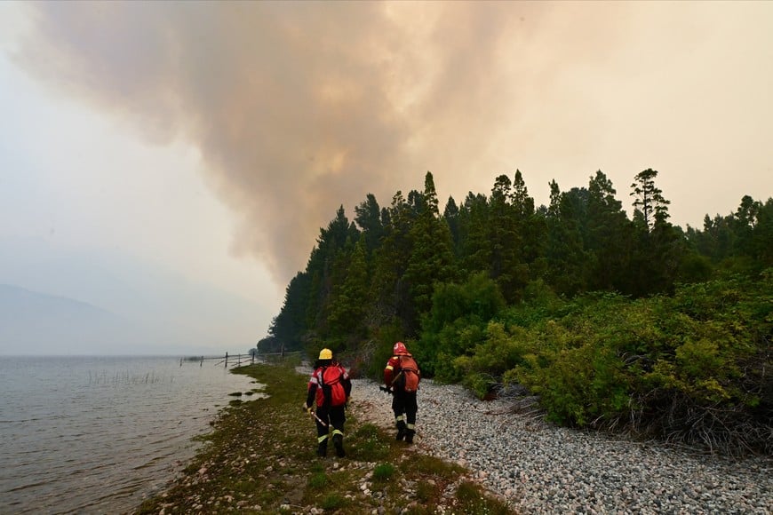 Brigades walk along the shore of the Lago Epuyen during a wildfire, in the Patagonian province of Chubut, Argentina January 7, 2026. REUTERS/Maxi Jonas