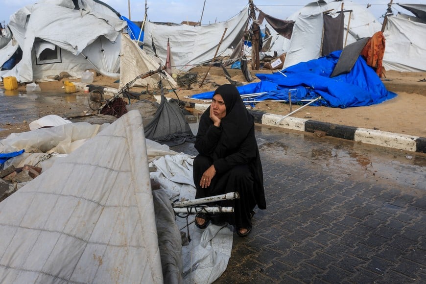 A displaced Palestinian woman sits near damaged tents, amid a windstorm, in Gaza City, January 13, 2026. REUTERS/Dawoud Abu Alkas
