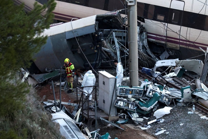 A firefighter and members of the Spanish Civil Guard work next to one of the trains involved in the accident, at the site of a deadly derailment of two high-speed trains near Adamuz, in Cordoba, Spain, January 19, 2026. REUTERS/Susana Vera