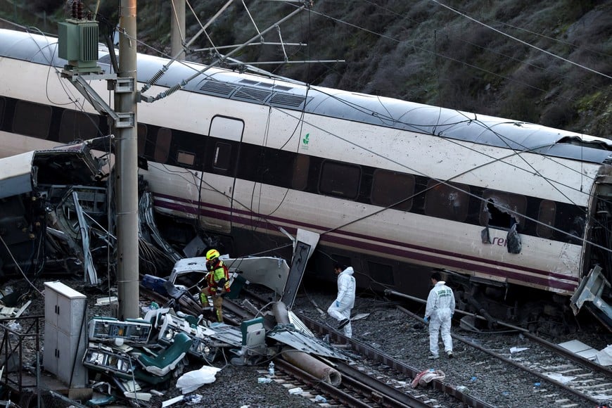 A firefighter and members of the Spanish Civil Guard work next to one of the trains involved in the accident, at the site of a deadly derailment of two high-speed trains near Adamuz, in Cordoba, Spain, January 19, 2026. REUTERS/Susana Vera