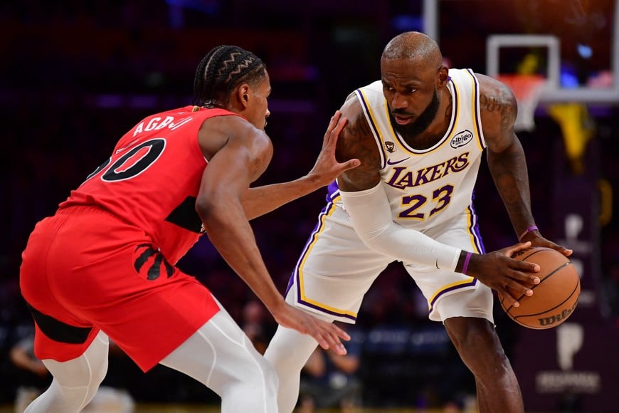 Jan 18, 2026; Los Angeles, California, USA; Los Angeles Lakers forward LeBron James (23) controls the ball against Toronto Raptors guard Ochai Agbaji (30) during the first half at Crypto.com Arena. Mandatory Credit: Gary A. Vasquez-Imagn Images