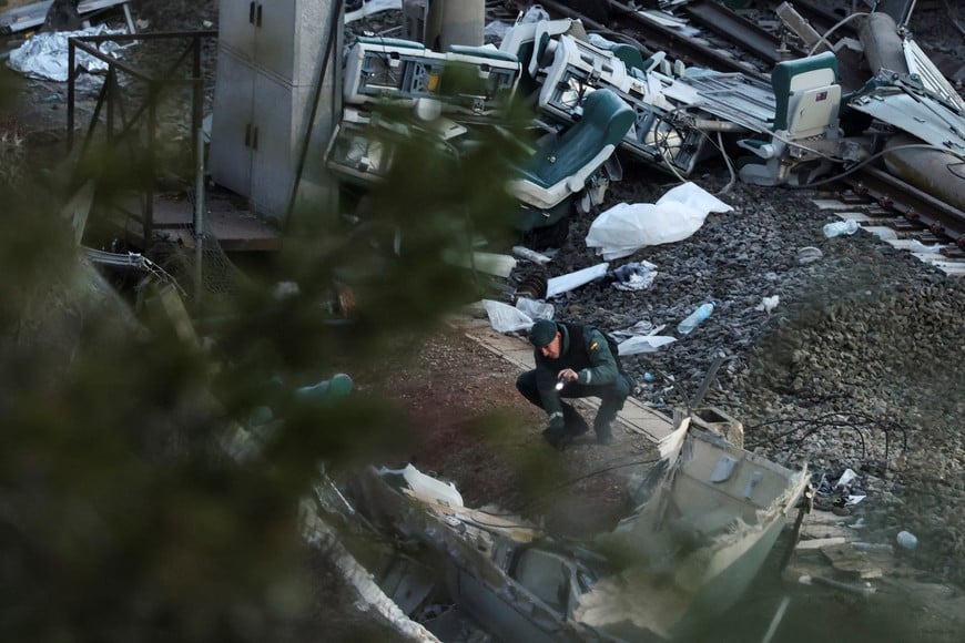 A member of the Spanish Civil Guard searches with his flashlight through the wreckage of a train involved in the accident, at the site of a deadly derailment of two high-speed trains near Adamuz, in Cordoba, Spain, January 20, 2026. REUTERS/Susana Vera