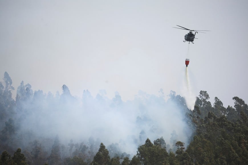 A helicopter drops water to fight a fire in the Biobio region, where multiple wildfires prompted emergency evacuations, in Concepcion, Chile January 19, 2026. REUTERS/Adriano Machado