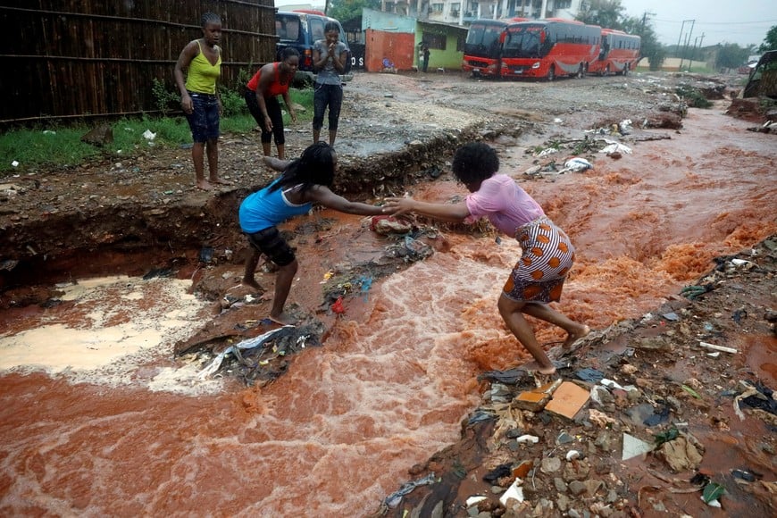 A woman crosses a flooded street in the aftermath of Cyclone Kenneth in Pemba, Mozambique, April 28, 2019. REUTERS/Mike Hutchings