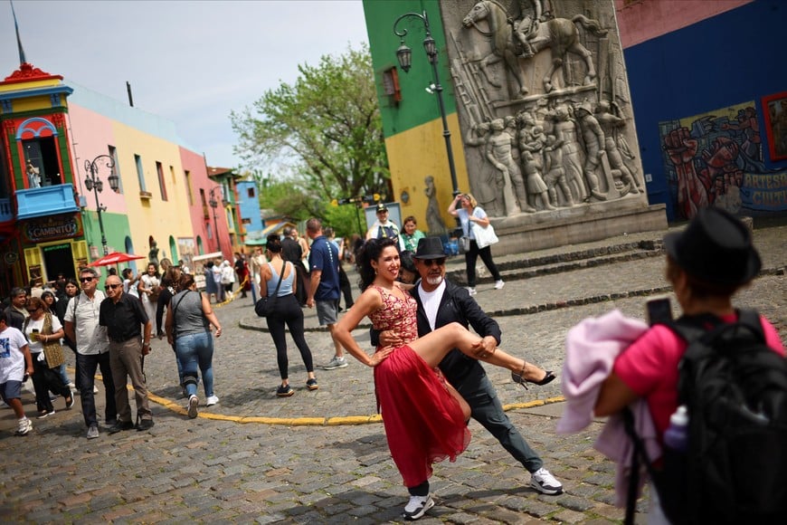 A tourist poses for a picture with a Tango dancer, at Caminito, in La Boca neighborhood of Buenos Aires, Argentina, October 10, 2025. REUTERS/Agustin Marcarian
