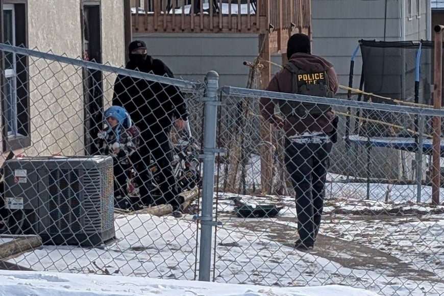ICE agents stand next to a boy, who a witness identified as Liam Conejo Ramos, a five-year-old that  school officials said was detained in Minneapolis, Minnesota, U.S., January 20, 2026.  Rachel James/via REUTERS  THIS IMAGE HAS BEEN SUPPLIED BY A THIRD PARTY. MANDATORY CREDIT. Reuters verified the location from the road layout, buildings, and fence seen in the video and photographs which matched file and satellite imagery of the area. The date when the visuals were filmed was confirmed by the original file metadata. The school district officials said that a five-year-old was detained on Tuesday (January 20). The Department of Homeland Security said they attempted to apprehend the father of the boy on Tuesday (January 20.). THIS PICTURE WAS CROPED BY REUTERS. AN UNCROPED VERSION HAS BEEN PROVIDED SEPARATELY.     TPX IMAGES OF THE DAY