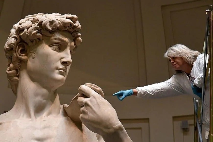 En esta imagen de 2022 puede verse a Eleonora Pucci, restauradora interna de la Gallería de la Academia de Florencia, señalando un detalle de la célebre escultura David, de Miguel Ángel Buonarroti. Realizada en mármol blanco, tiene 5,17 metros de altura y pesa 5.572 kilogramos. Fue un encargo de la Opera del Duomo de la catedral de Santa María del Fiore.