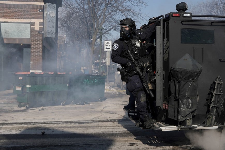 A Minneapolis Police Department officer rides on the back of a vehicle, during clashes with community members at the scene where federal agents fatally shot a man while trying to detain him, in Minneapolis, Minnesota, U.S., January 24, 2026. REUTERS/Tim Evans