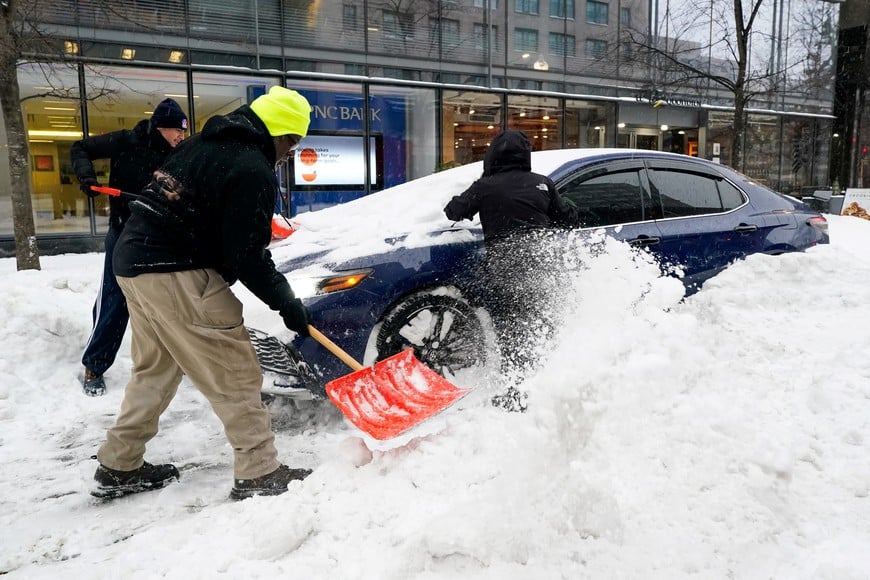 People dig out a parked car buried by snow pushed by plows as a major winter storm spreads across a large swath of the United States, in Washington, D.C., U.S., January 25, 2026. REUTERS/Elizabeth Frantz
