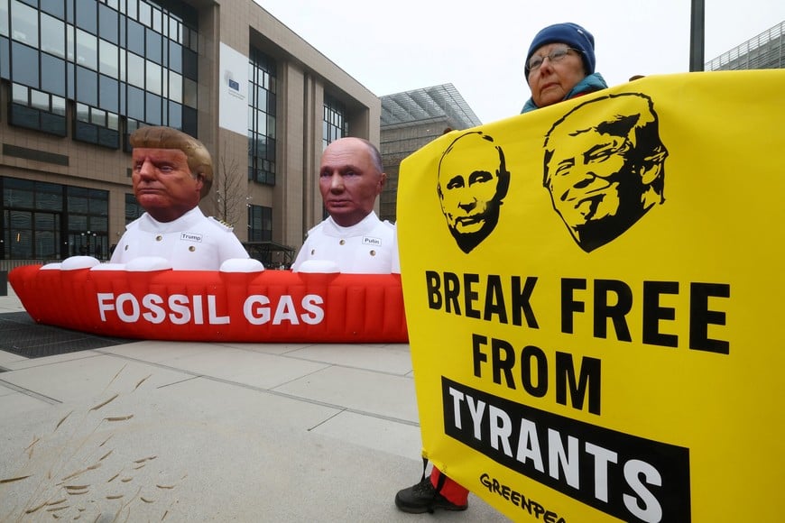 An environmantal activist from Greenpeace holds a placard, during a protest next to a giant inflatable gas tanker featuring figures of Russian President Vladimir Putin and U.S. President Donald Trump in Brussels, Belgium January 26, 2026.  REUTERS/Yves Herman