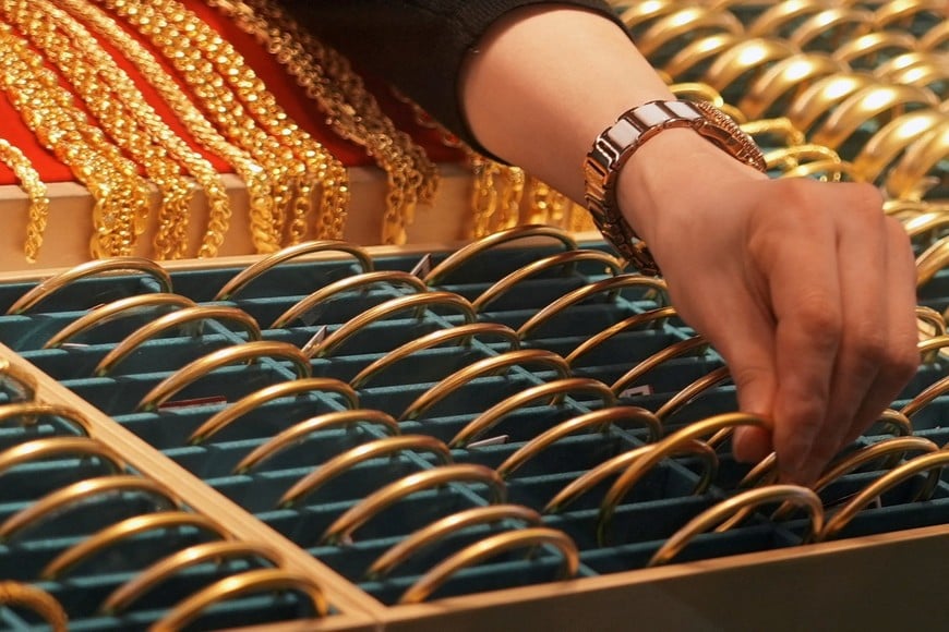 A shopkeeper adjusts gold bracelets on display at a jewellery mall in Shanghai, China January 27, 2026. REUTERS/Nicoco Chan