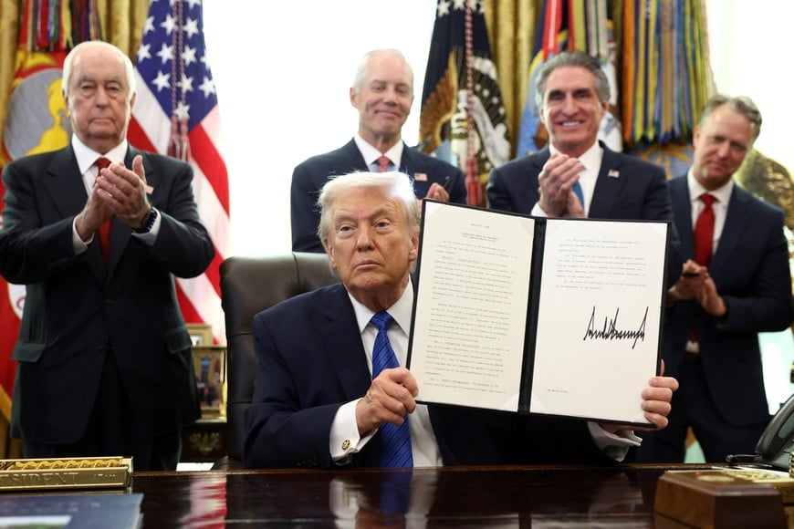 Roger Penske, businessman and former race car driver, and U.S. Secretary of the Interior Doug Burgum applaud as U.S. President Donald Trump holds an executive order he signed in the Oval Office, at the White House in Washington, D.C., U.S., January 30, 2026. REUTERS/Kevin Lamarque