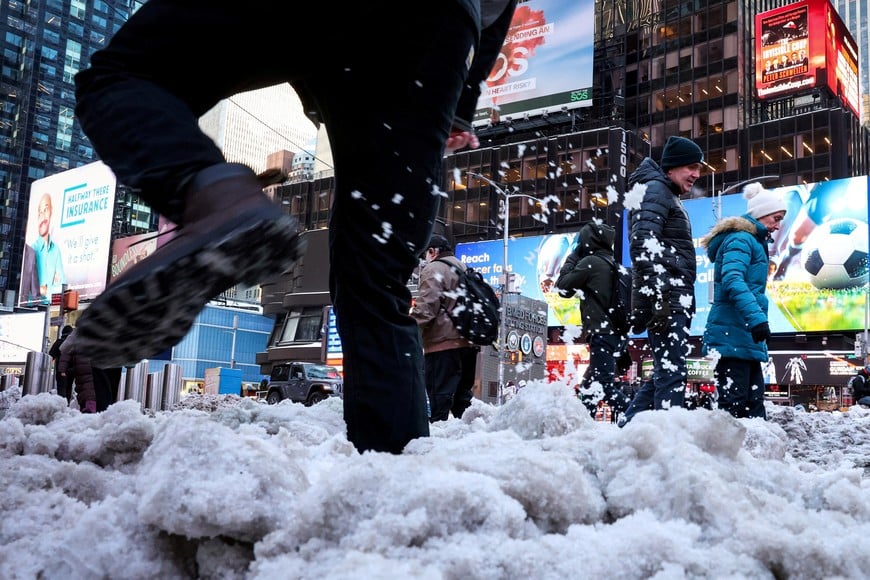 Morning commuters walk through snow in Times Square, following a major winter storm that had spread through a large swath of the United States, in New York City, U.S., January 27, 2026.  REUTERS/Brendan McDermid