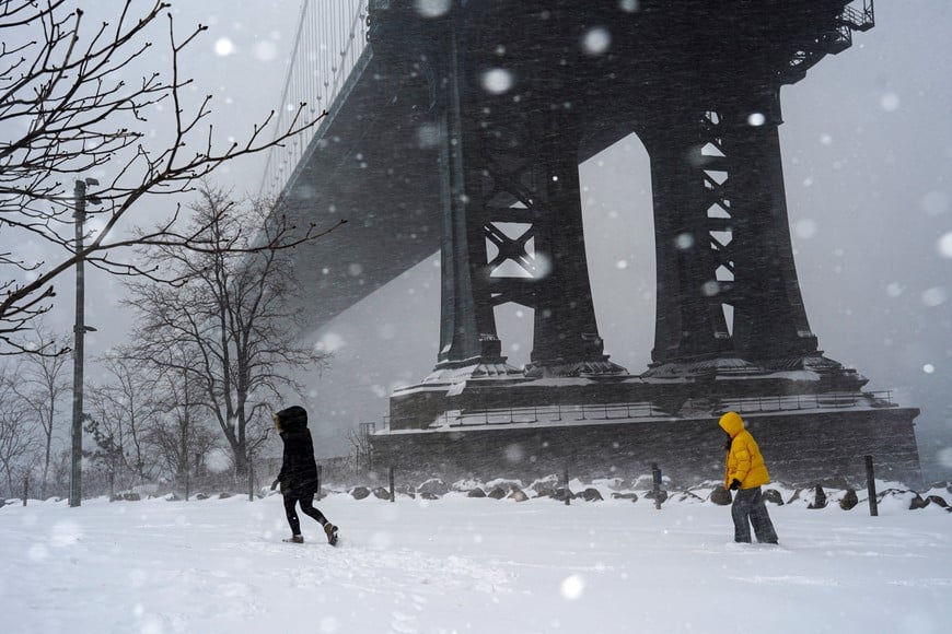 People walk under the Manhattan Bridge as a major winter storm spreads across a large swath of the United States, in New York City, U.S., January 25, 2026. REUTERS/Bing Guan