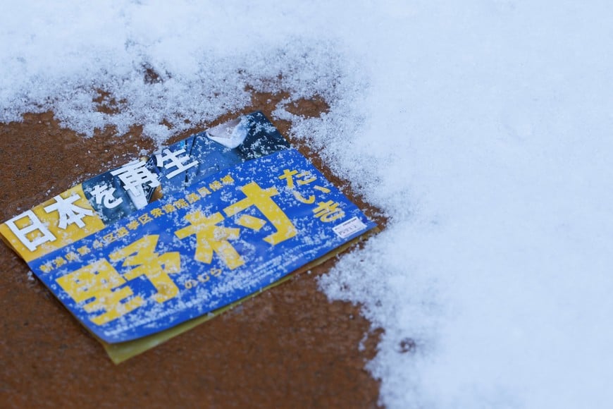 A campaign flyer lies buried in snow, ahead of the February 8 snap election, in Nagaoka, Japan, February 7, 2026. REUTERS/Manami Yamada