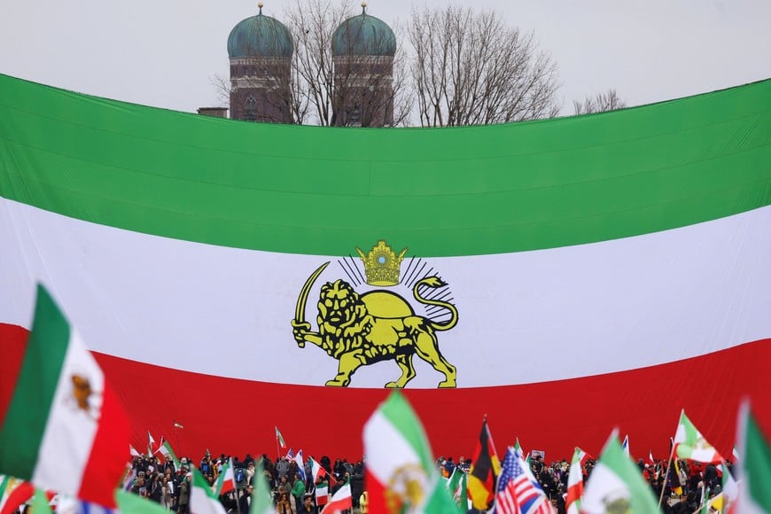 Protesters gather under a huge "Lion and Sun" pre-Iranian Revolution national flag, placed in front of Munich’s famous Church of Our Lady Liebfrauenkirche, during a demonstration organised by The Munich Circle calling for a free Iran, during the Munich Security Conference (MSC), in Munich, Germany, February 14, 2026. REUTERS/Thilo Schmuelgen