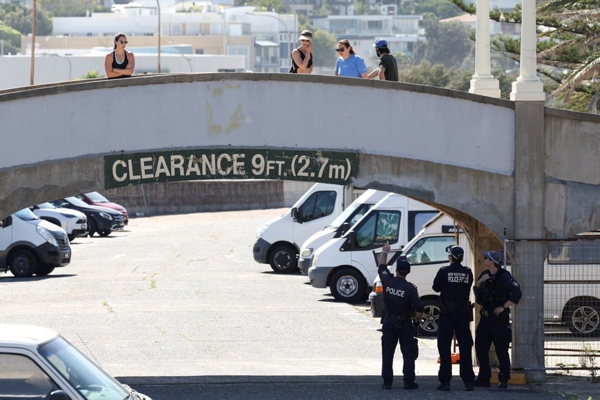 Police officers stand under the bridge as the crime scene was reopened following the mass shooting at Bondi Beach on Sunday, in Sydney, Australia, December 19, 2025. REUTERS/Hollie Adams     TPX IMAGES OF THE DAY