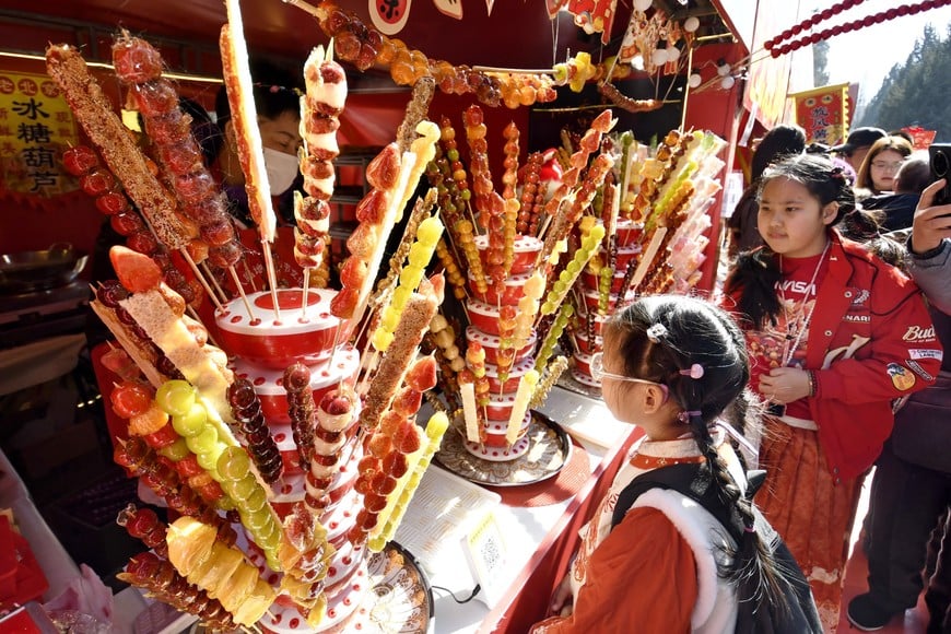 (260217) -- BEIJING, 17 febrero, 2026 (Xinhua) -- Personas compran Tanghulu, un aperitivo tradicional chino compuesto por bayas o frutas recubiertas de azúcar, en una feria de templo, en Beijing, capital de China, el 17 de febrero de 2026. Las ferias de templo se inauguraron aquí para celebrar la Fiesta de la Primavera y ofrecer a los visitantes bailes tradicionales, danzas del león y deliciosa comida. (Xinhua/Li Xin) (oa) (ah) (vf)