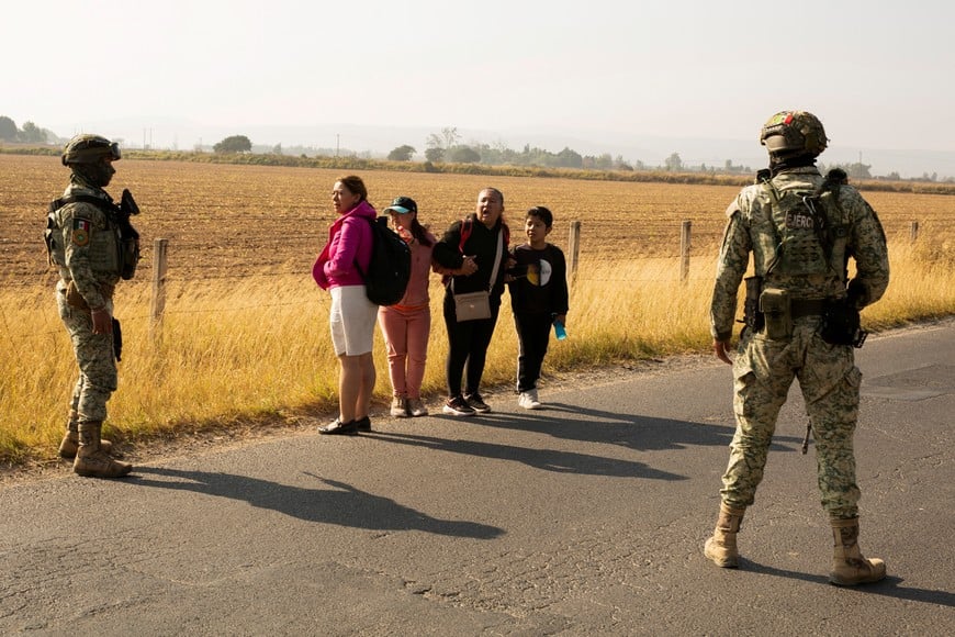 Soldiers stop people from passing near a burning bus used as a roadblock by organized crime following a federal operation in which a government source said Mexican drug lord Nemesio Oseguera, commonly known as "El Mencho," was killed, in Zapopan, Mexico, February 22, 2026. REUTERS/Gabriel Trujillo