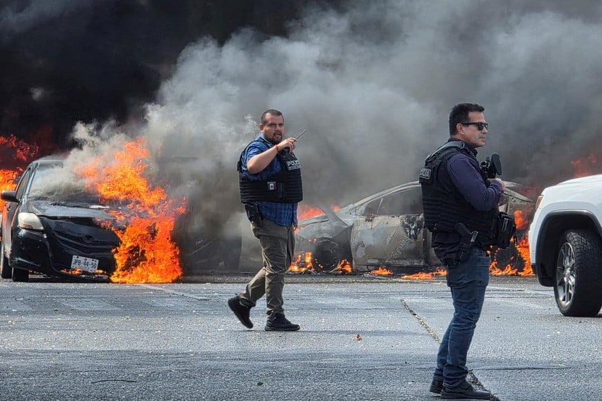 Police officers secure the area where vehicles were set on fire by organized crime members to block a road following a military operation in which a government source said Mexican drug lord Nemesio Oseguera, commonly known as "El Mencho," was killed, in Zapopan, Mexico, February 22, 2026. REUTERS/Gilberto Gallo     TPX IMAGES OF THE DAY