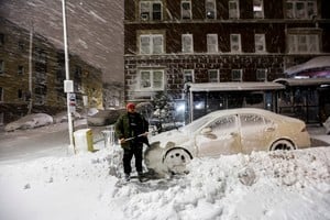 A man removes snow to drive his car as snow falls down during a winter storm in West New York, New Jersey, U.S., February 23, 2026. REUTERS/Eduardo Munoz