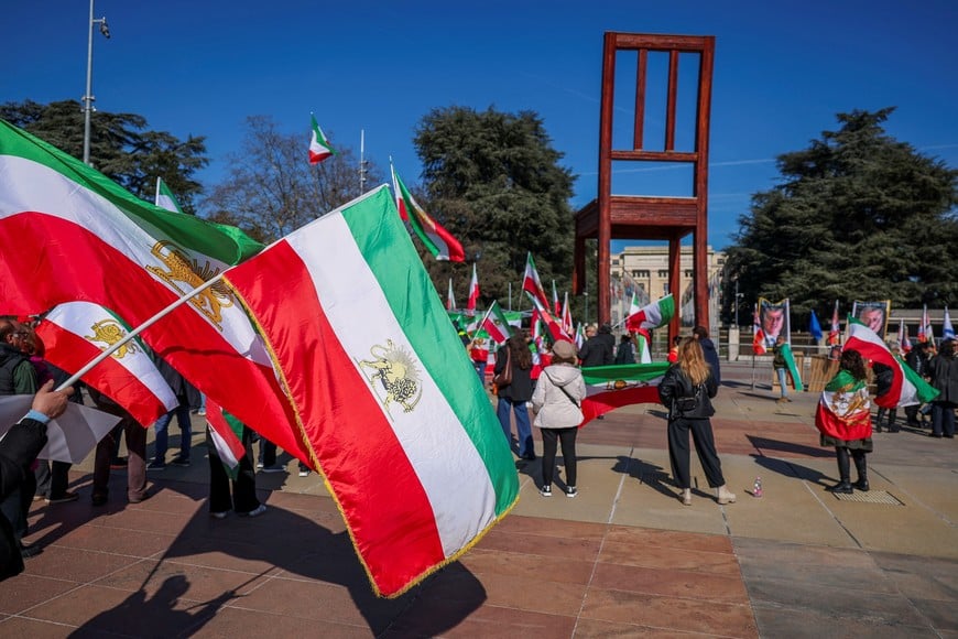 People hold the "Lion and Sun" pre-Iranian Revolution national flags during a protest against Iran's government in front of the United Nations Office at Geneva, on the day of a new round of indirect U.S.-Iran talks over their long-running nuclear dispute, in Geneva, Switzerland, February 26, 2026. REUTERS/Pierre Albouy