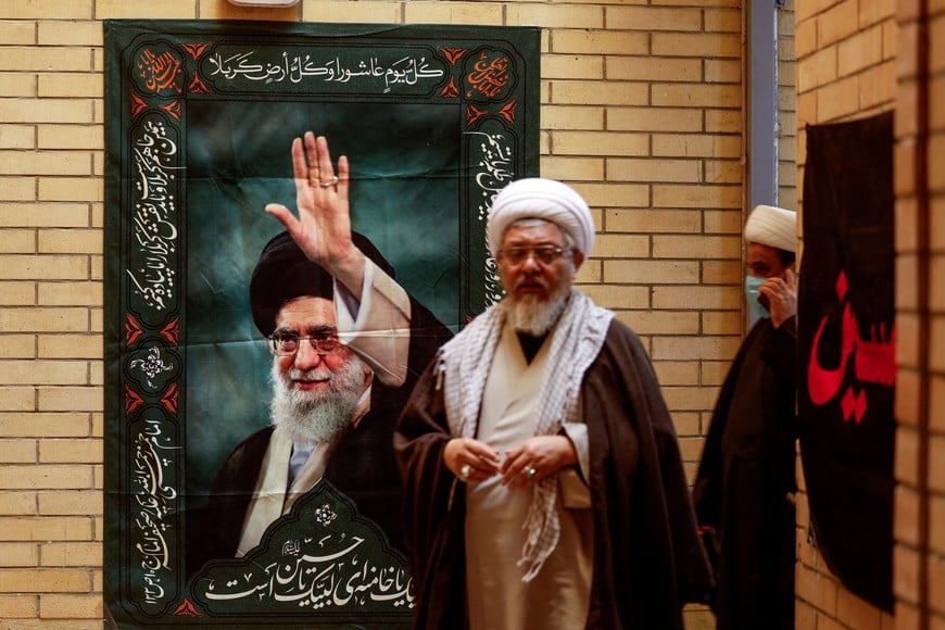 Clerics walk past a wall with a poster of Iran's Supreme Leader Ayatollah Ali Khamenei, after offering their condolences following his killing in Israeli and U.S. strikes, at the office of the Supreme Leader's representative in Najaf, Iraq, March 1, 2026. REUTERS/Alaa al Marjani TPX IMAGES OF THE DAY